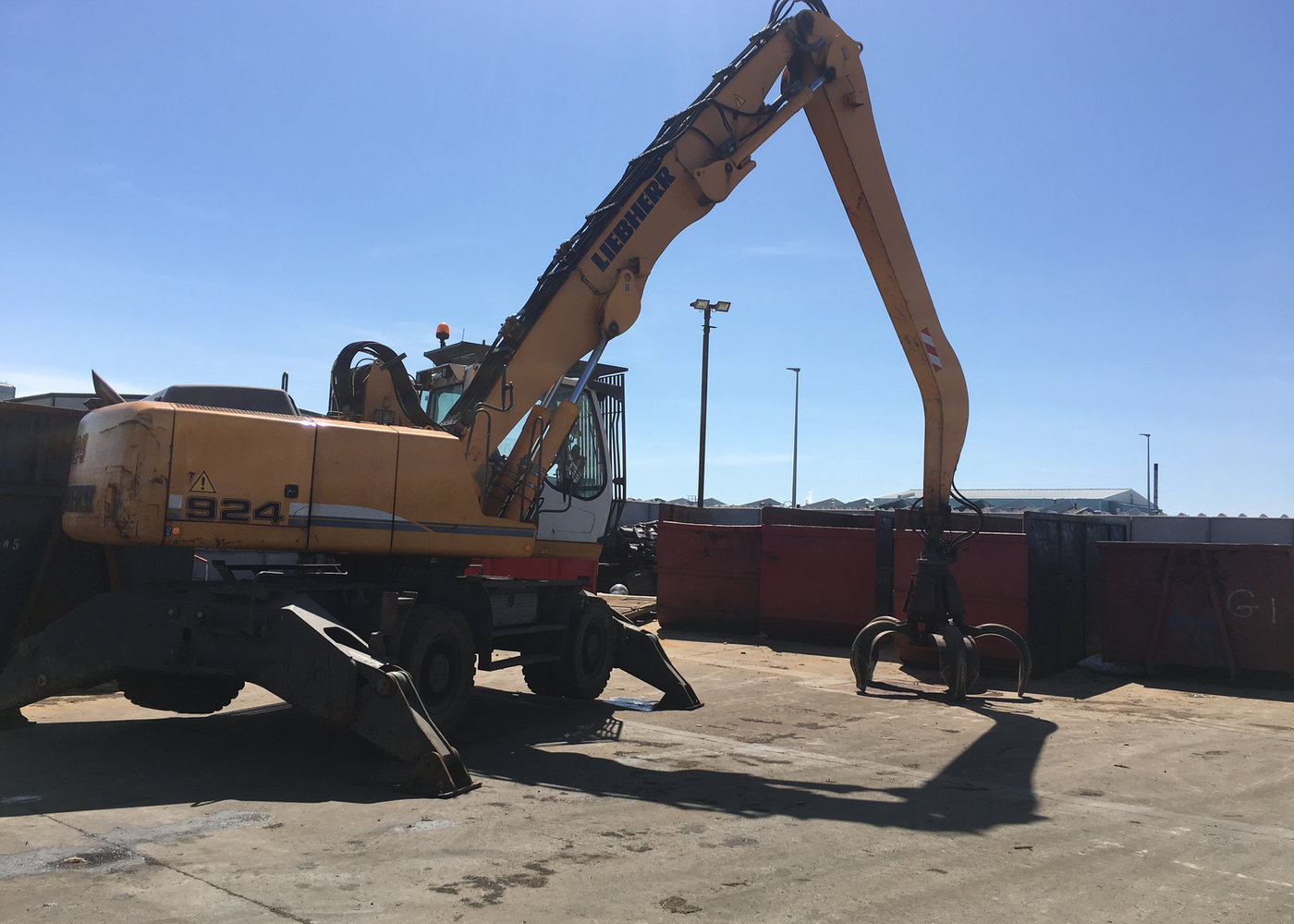 Material handler loading ferrous scrap into a container in the yard