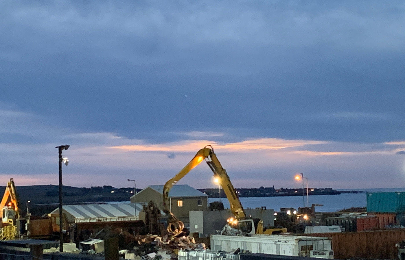 Natdian Recycling Centre yard at dusk with sorted scrap steel and stacked oilfield pipe