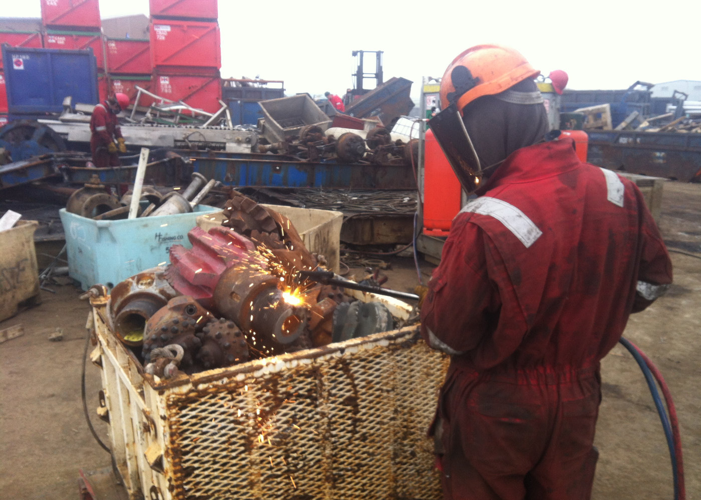 Operative in overalls cutting recovered equipment for material separation